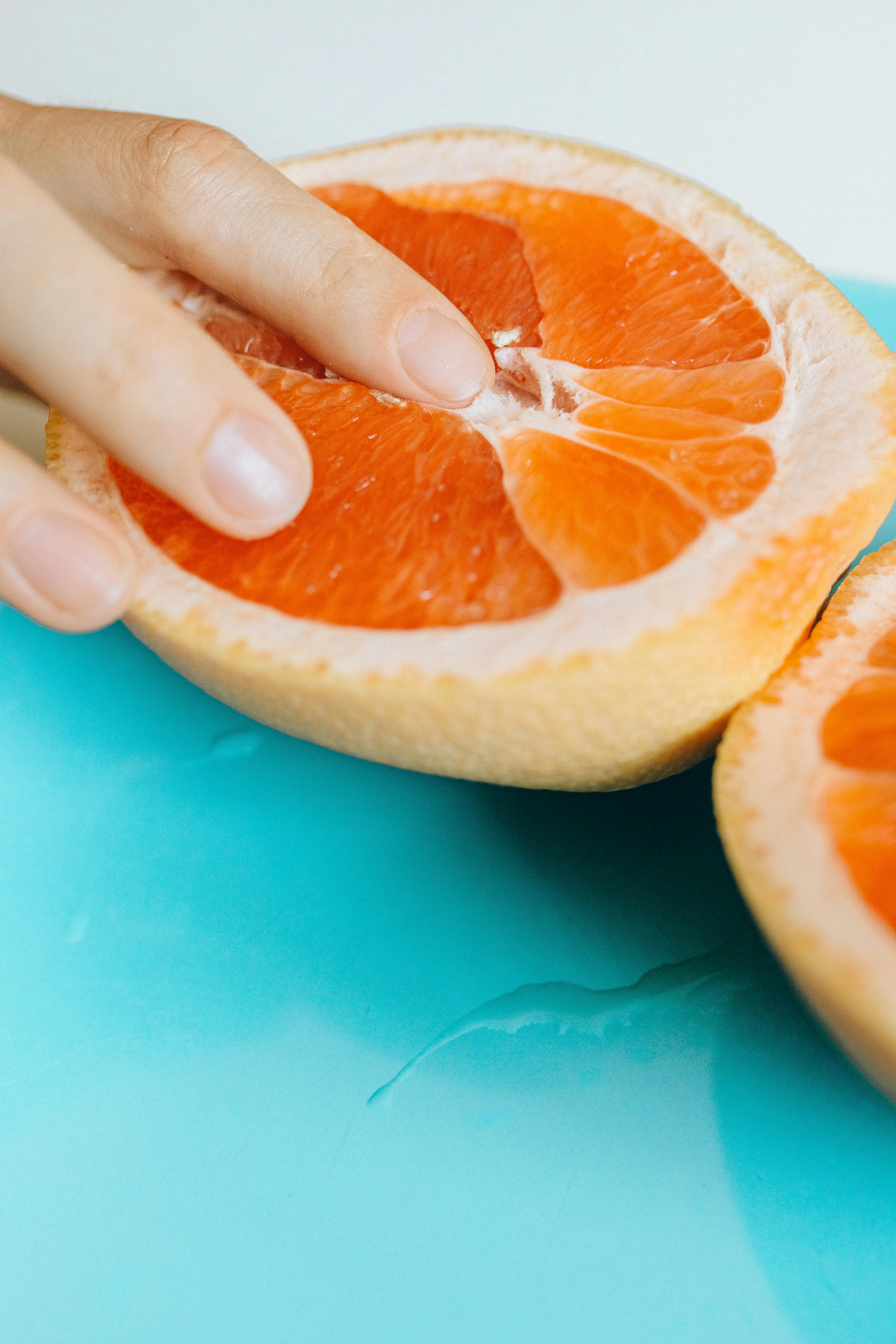 person touching sliced orange fruit