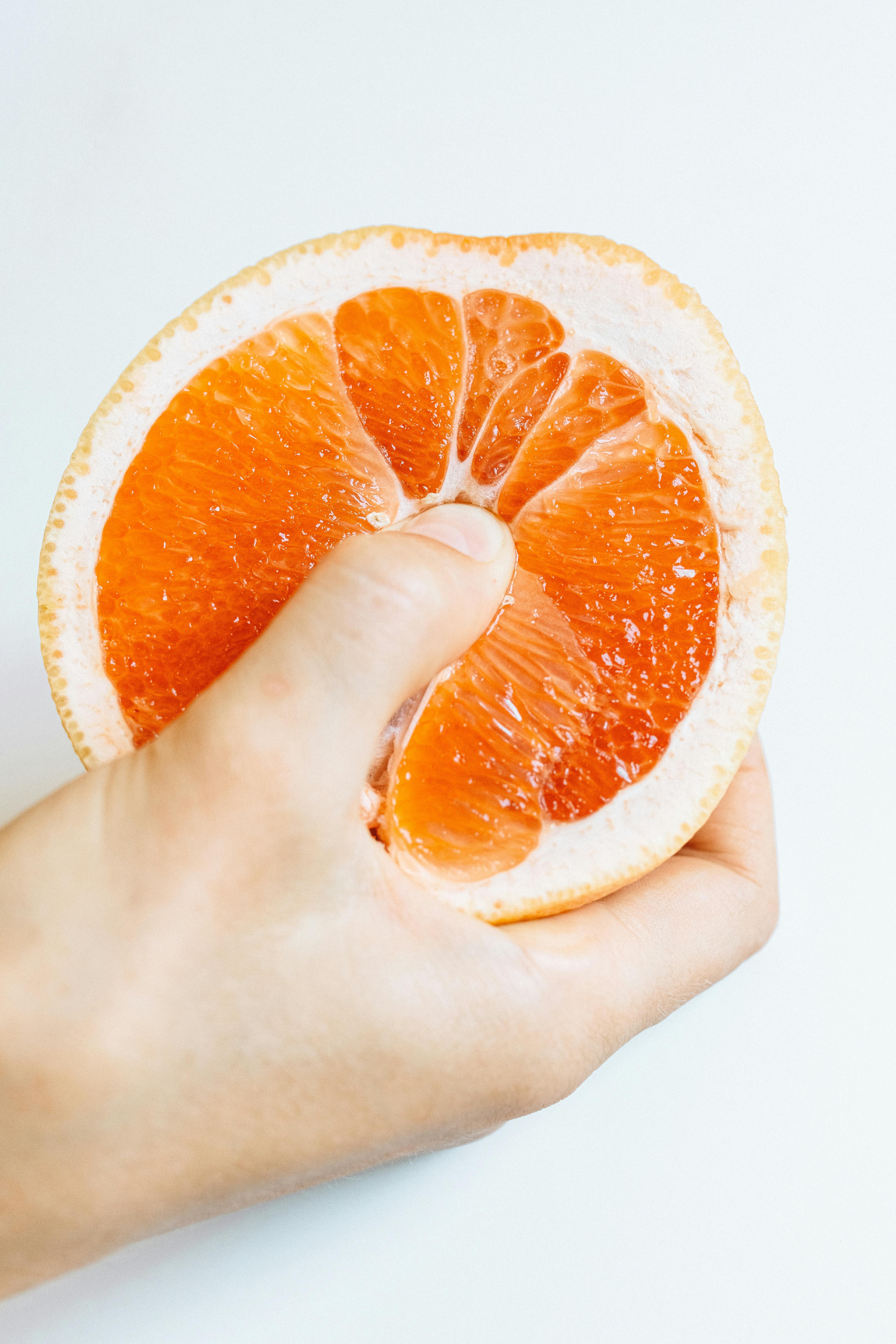 person holding sliced orange fruit