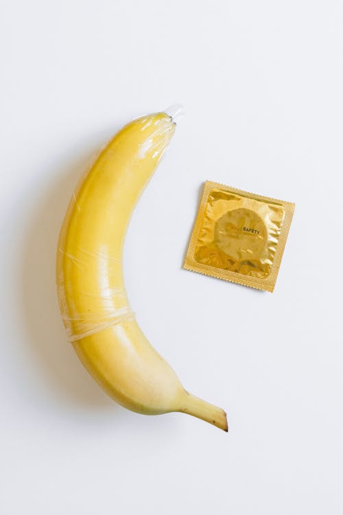 Free Condom Next to Yellow Banana Stock Photo