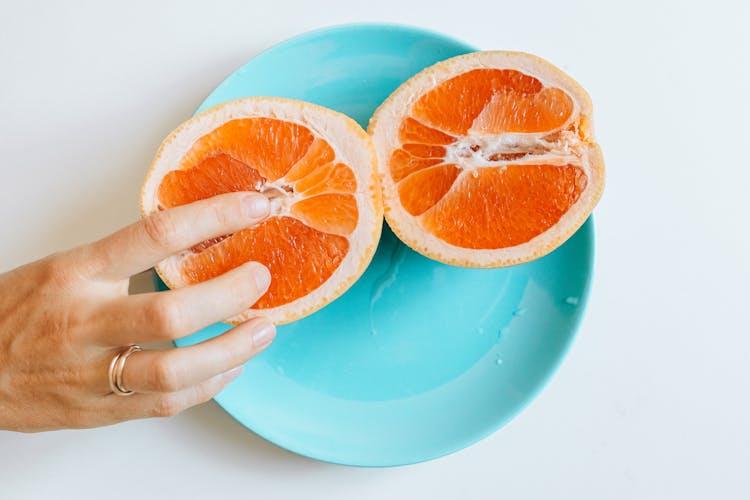 Person Touching Sliced Orange Fruit