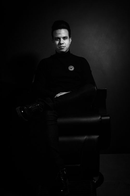 Free Black and white portrait of a man sitting with crossed legs in a turtleneck. Stock Photo