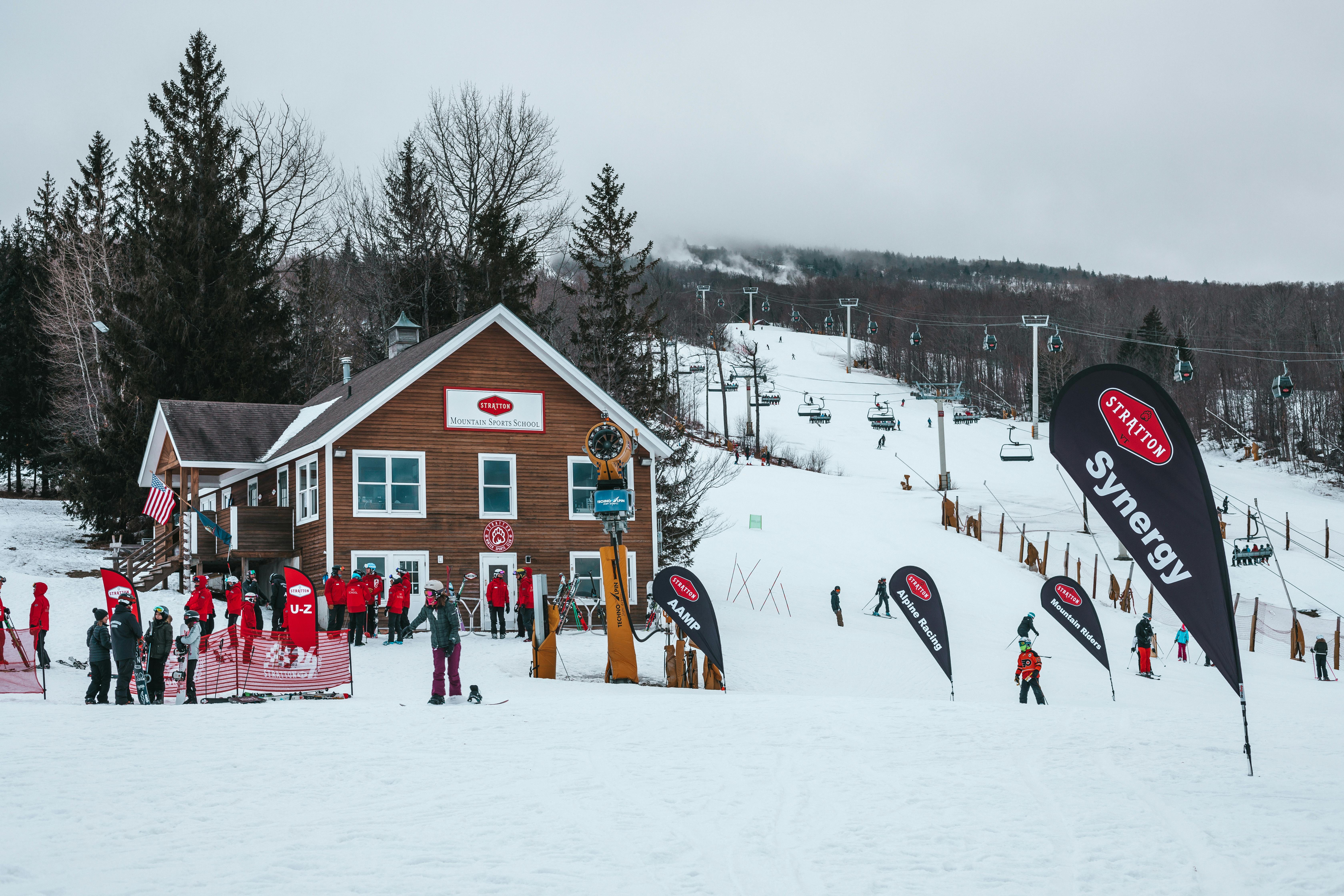 Ski resort scene with people enjoying winter sports amidst snowy mountains and trees.