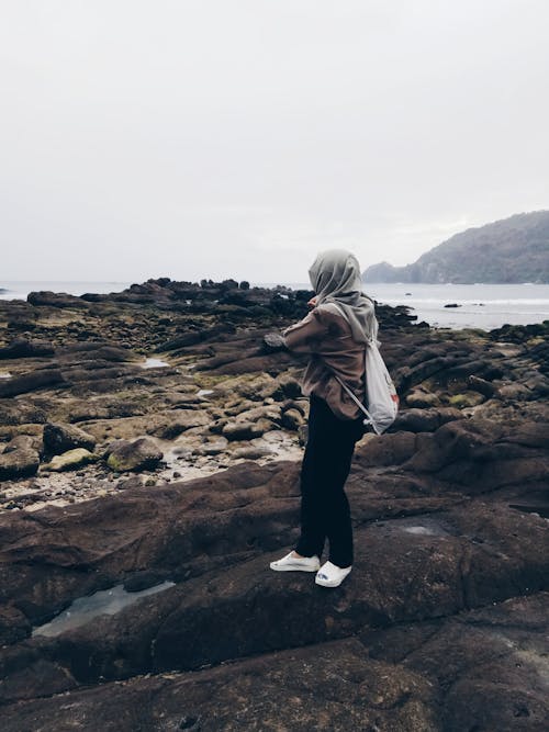 Kostenlos Person, Die In Der Nähe Der Küste Steht, Während Sie Einen Rucksack Mit Kordelzug Trägt Stock-Foto