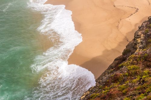 Free Dramatic waves crashing on the sandy shores of Nazaré beach, Portugal. Stock Photo