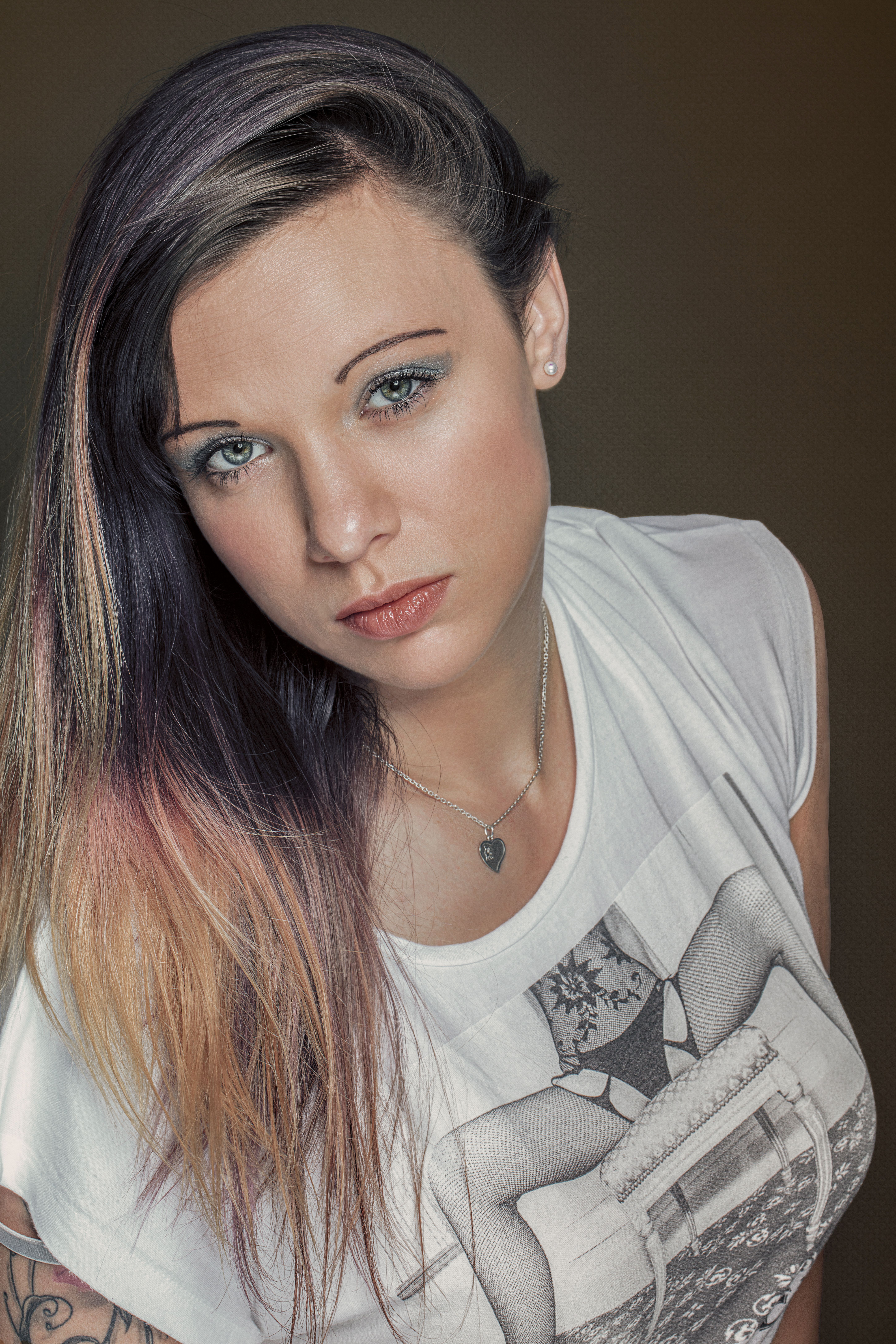 Elegant portrait of a woman with dyed hair, wearing a graphic tee and necklace, captured in a studio setting.