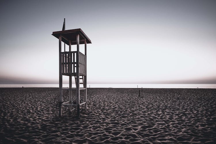 Lifeguard Tower On Empty Sandy Seashore At Sundown