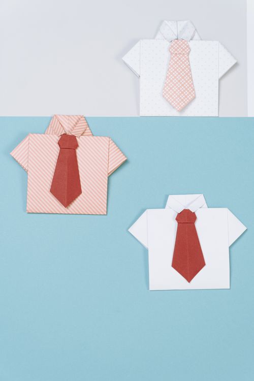 Free Origami paper shirts with ties arranged on a colorful background. Stock Photo