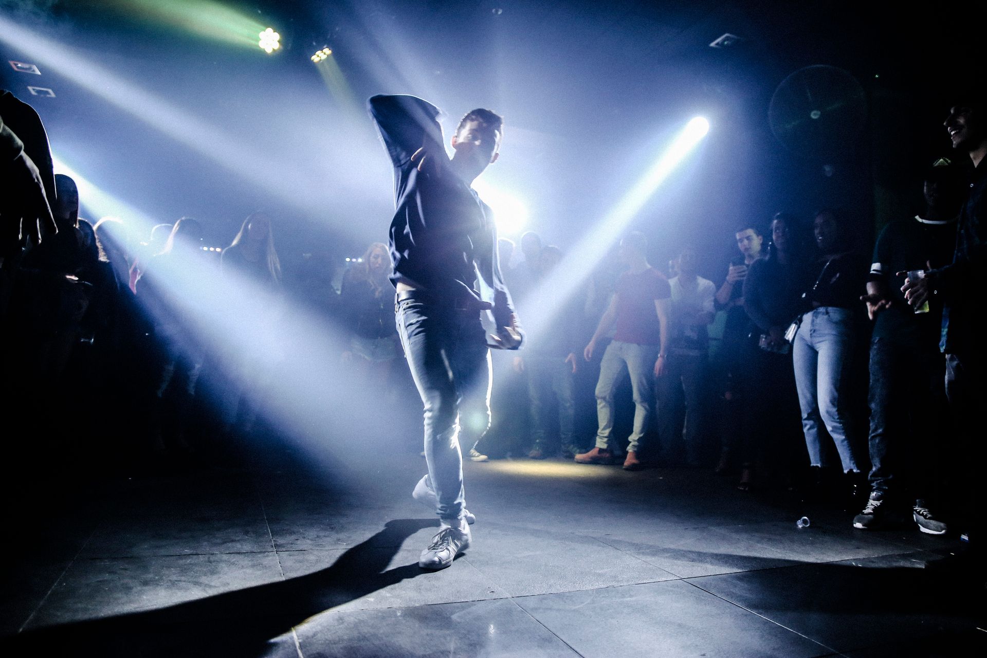 Performer under stage beams in a dark venue, photo by Maor Attias on Pexels