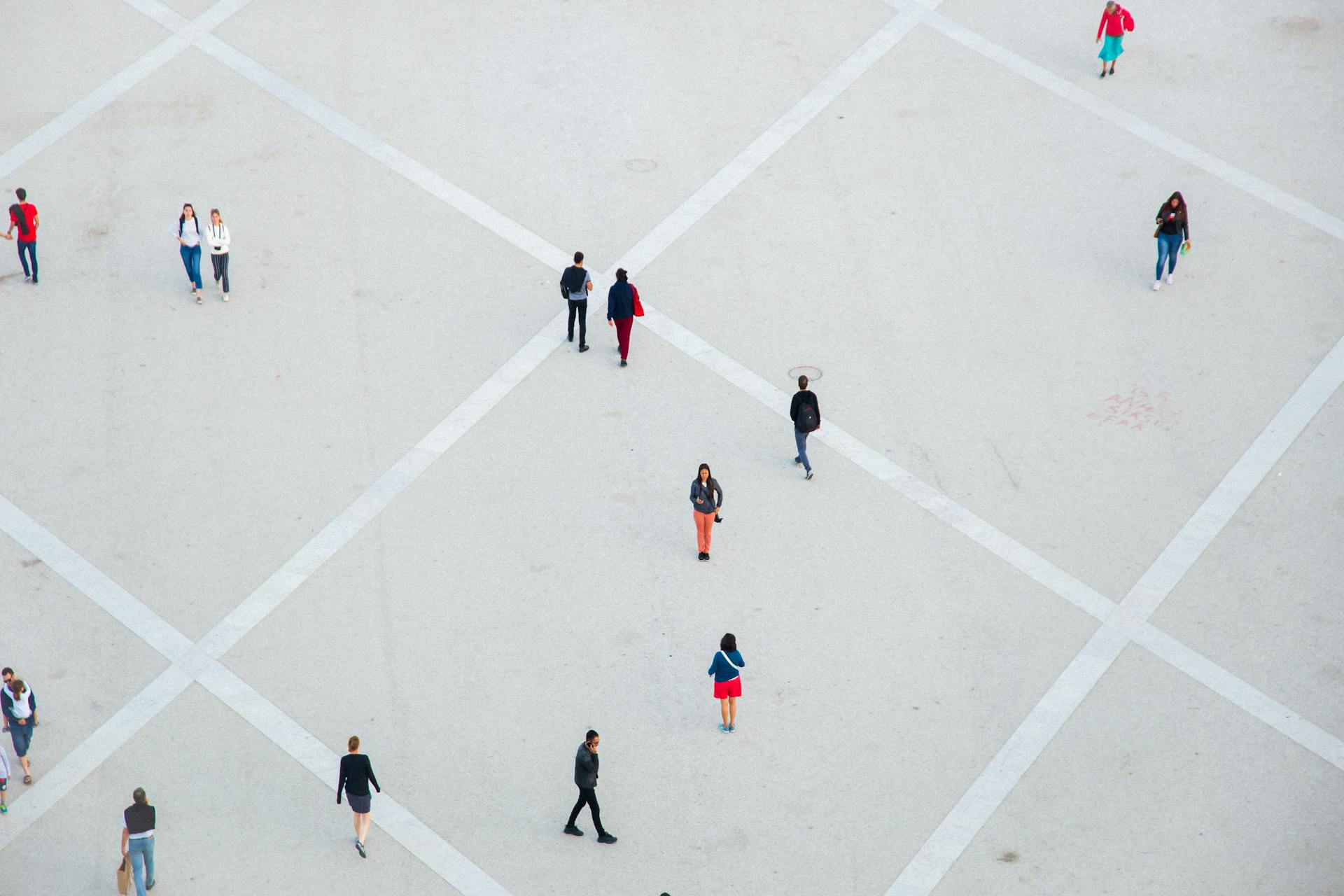 High angle citizens in casual wear walking on vast concrete ground in city square