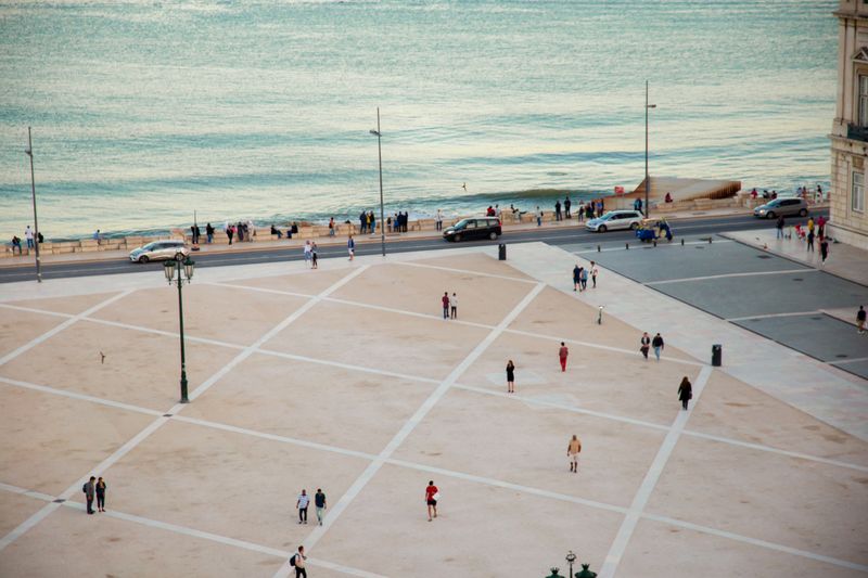 High angle citizens strolling on vast public square near rippling river located in coastal city in twilight