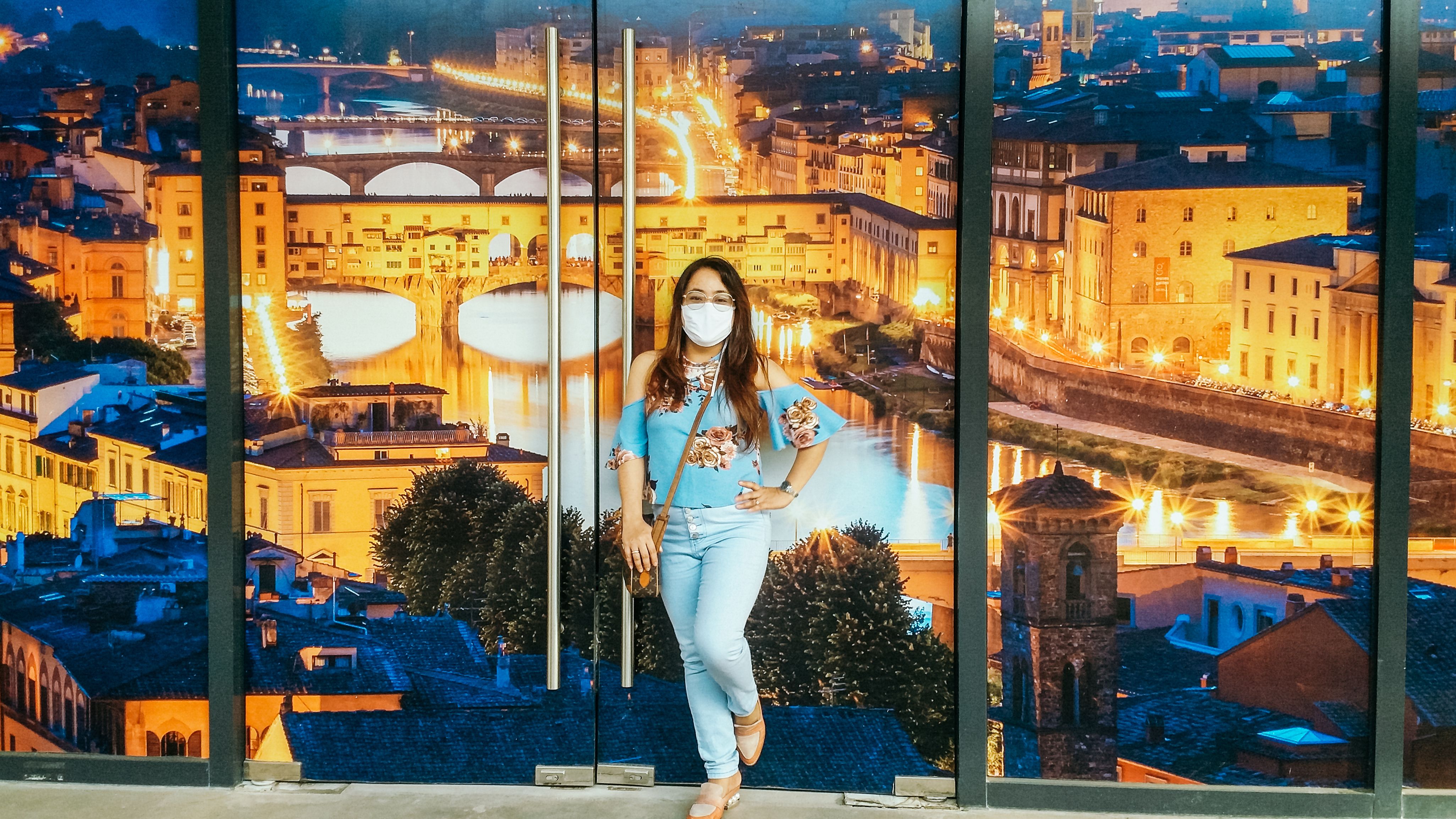 一位戴着口罩的年轻女子以巨大的城市景观为背景，在室内营造出都市氛围