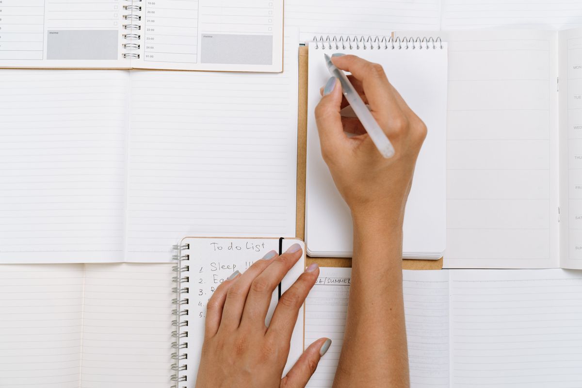 Hands writing a to-do list on notepads