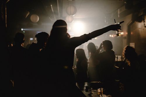 Free Silhouettes of people dancing and enjoying drinks at a bustling nightclub. Stock Photo