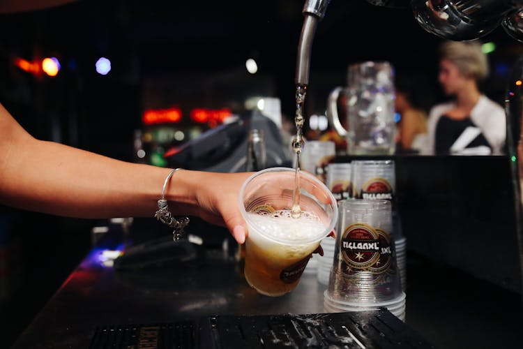 Bartender Pouring Beer On Plastic Cup