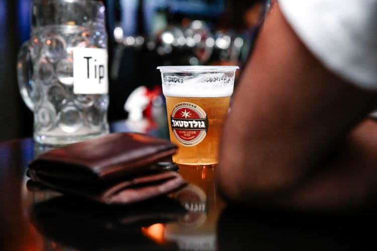 Leather Wallet And A Cup Of Beer On Bar Counter