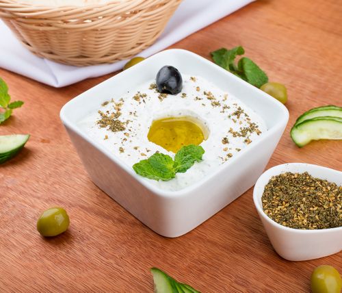 Free Close-up of tzatziki with olive oil, mint, and herbs served in a white bowl. Stock Photo