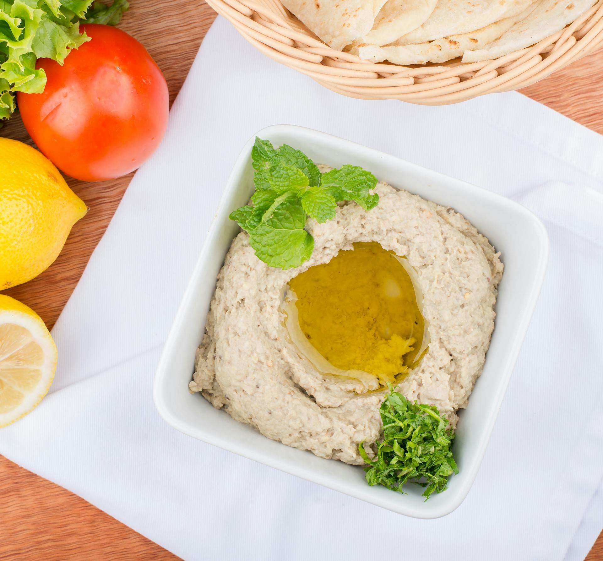 Delicious baba ghanoush with olive oil, surrounded by fresh vegetables and flatbread.