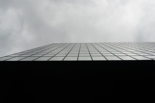 Low angle architectural view of a modern glass building facade in Düsseldorf under cloudy skies.
