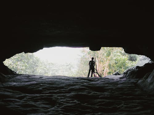 Free Man Standing Beside a Cave Stock Photo