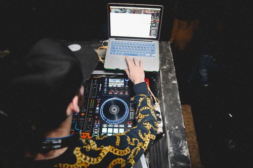 Free A DJ uses a laptop and mixing console during a vibrant live music event. Stock Photo