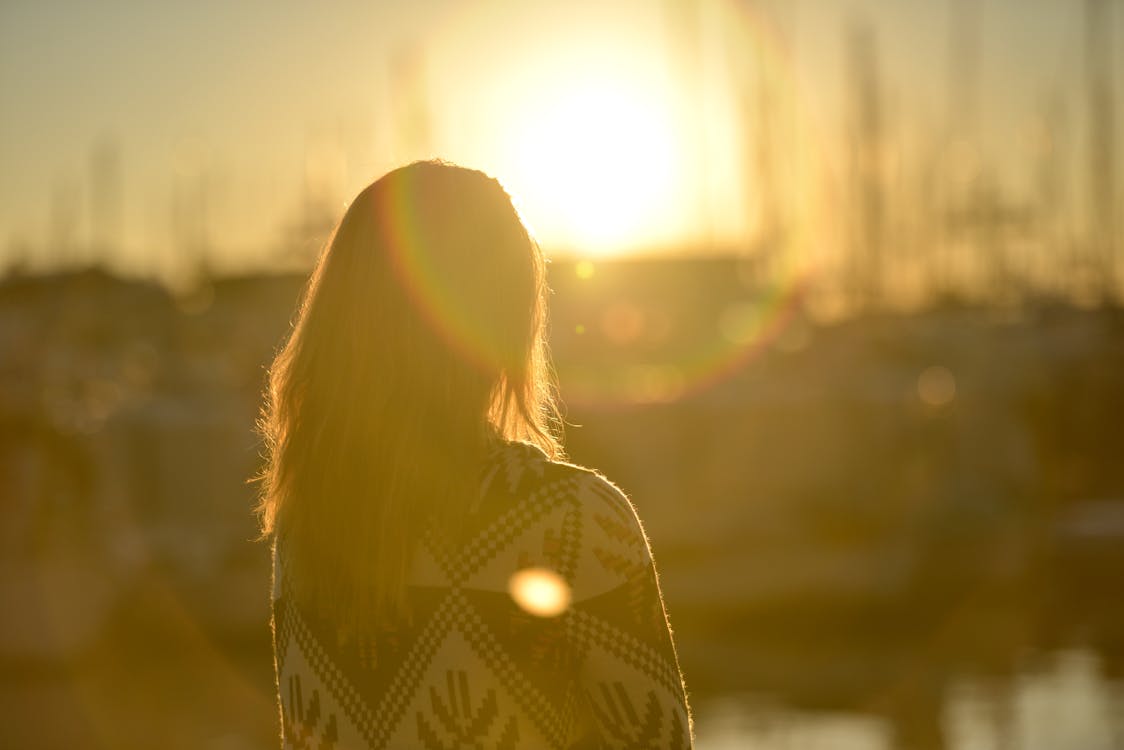 Free Woman Standing Against Facing Sun Stock Photo