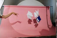 在粉色背景的工作室里，艺术家用手和飞行笔记本进行创作