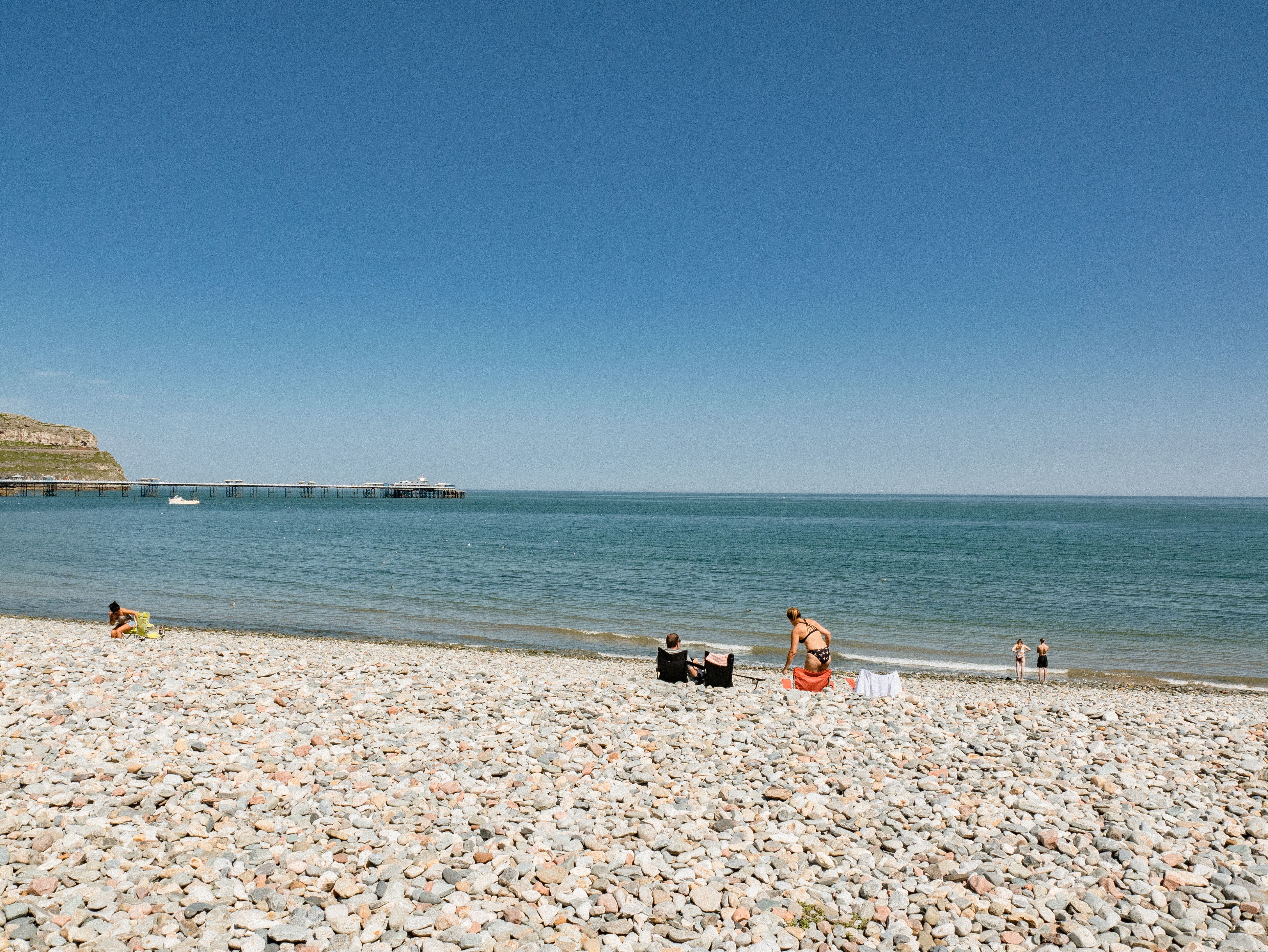 Enjoy a serene summer day at Llandudno's pebble beach with a scenic view of the sea.