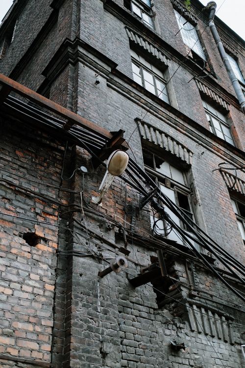 Free Low angle view of a grunge multistory building with exposed wires and brick exterior. Stock Photo