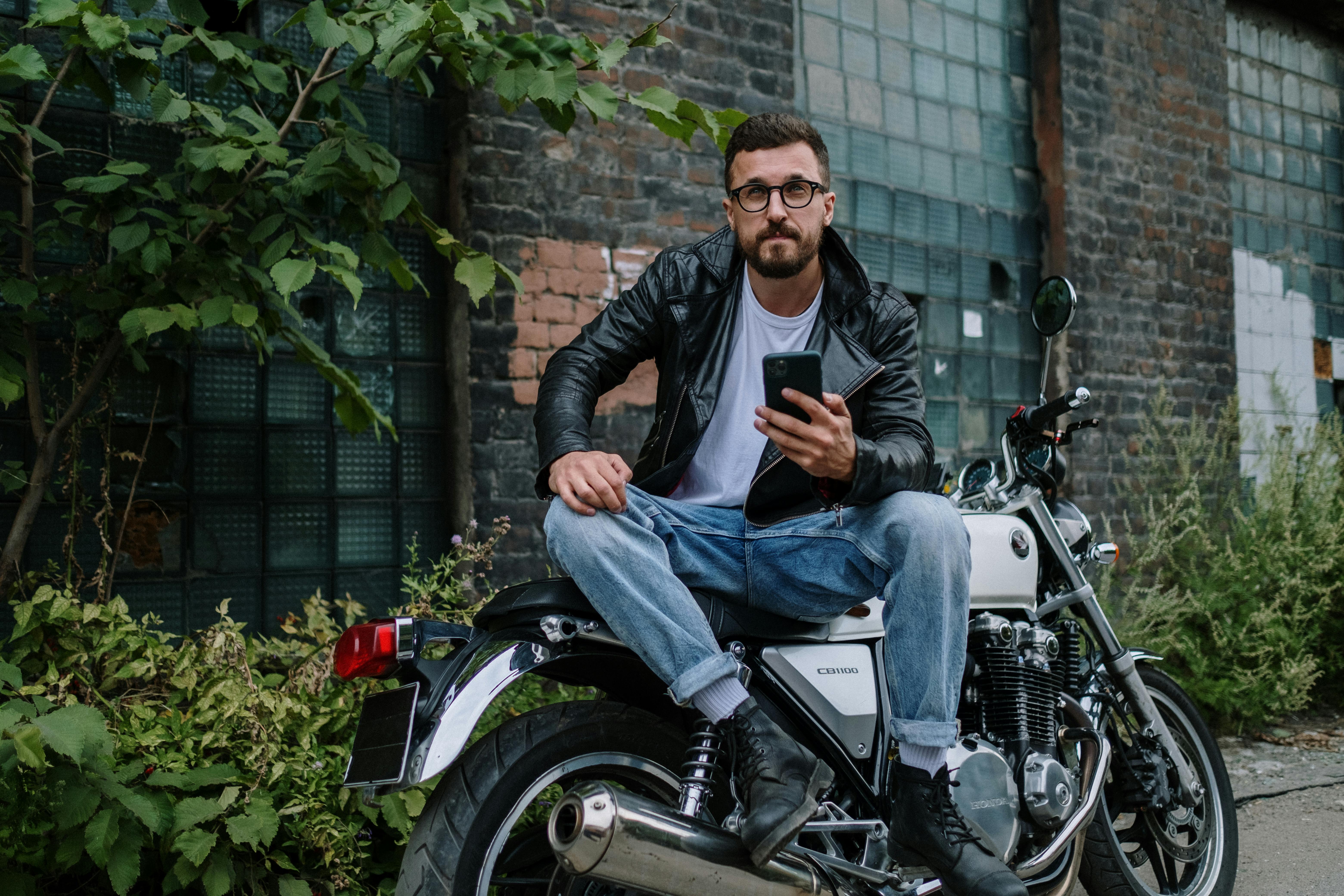 man wearing a black leather jacket sitting on a motorbike