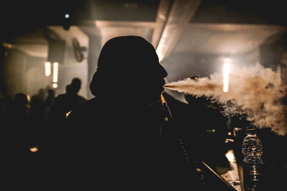 A person smoking hookah in a dimly lit bar with a relaxed nightlife ambiance