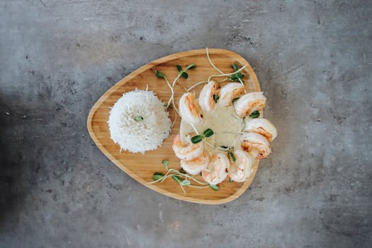 Top view of a shrimp and rice dish elegantly plated on a wooden serving tray.