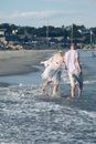 Man in White T-shirt and Blue Denim Shorts Walking on Beach