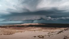 Capture of a dramatic sky over the dunes in Klaipėda County, Lithuania, with rain clouds looming.