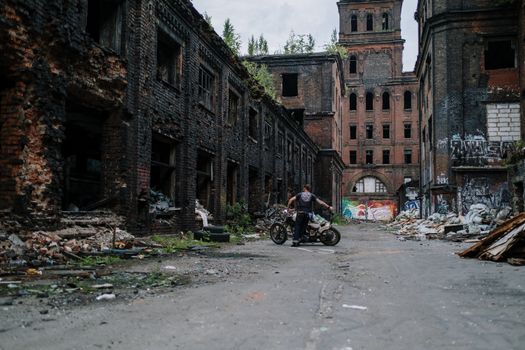 摩托车手探索一座废弃建筑，那里有涂鸦和腐烂的痕迹