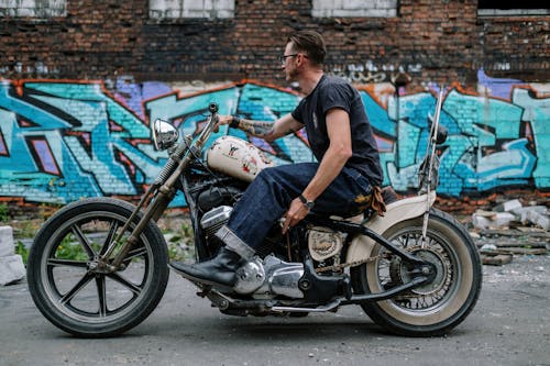 Man on Motorcycle Riding by Graffiti on Wall