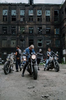 Group of bikers with motorcycles in front of an abandoned building.