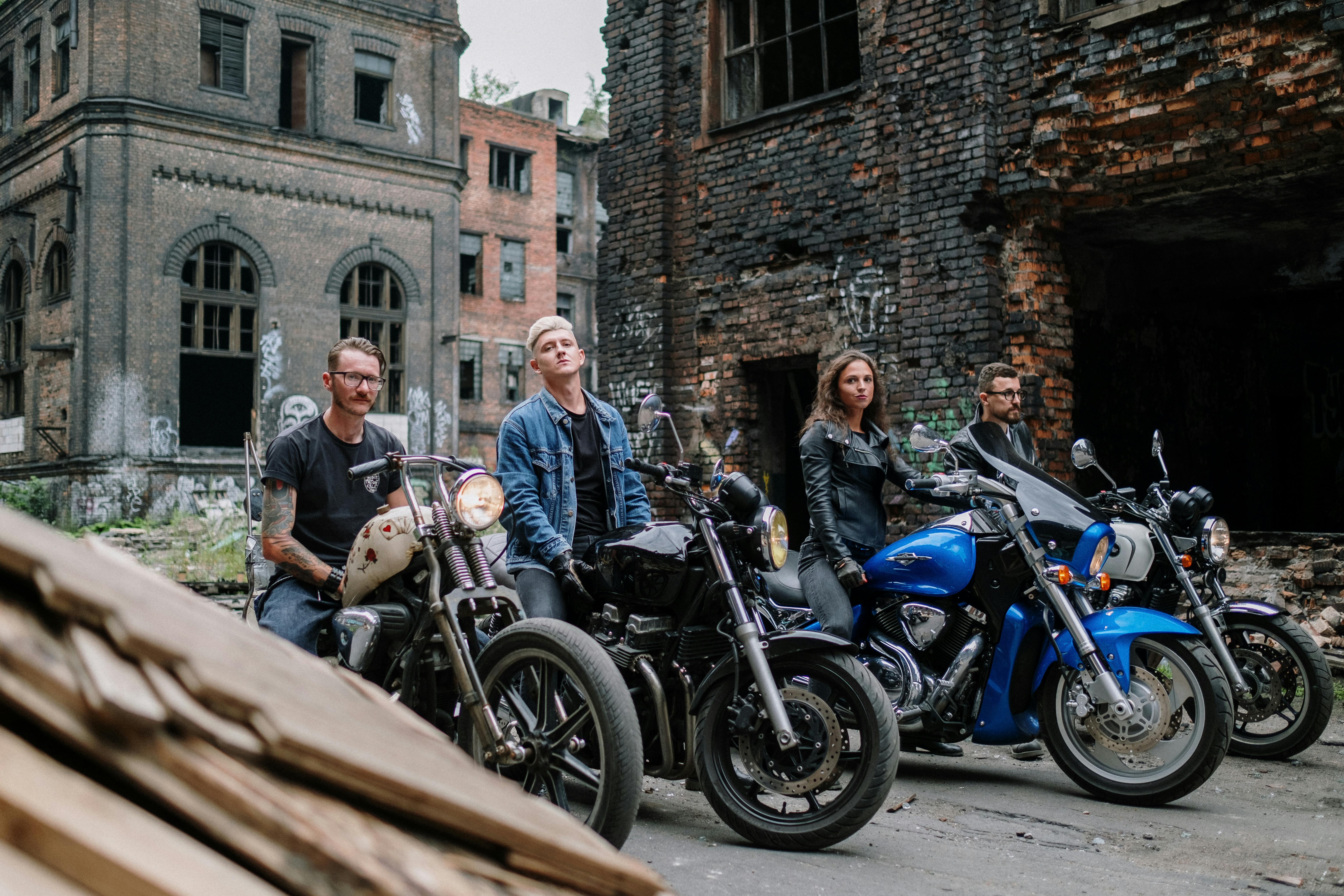 A diverse group of bikers on motorcycles in an abandoned urban setting.