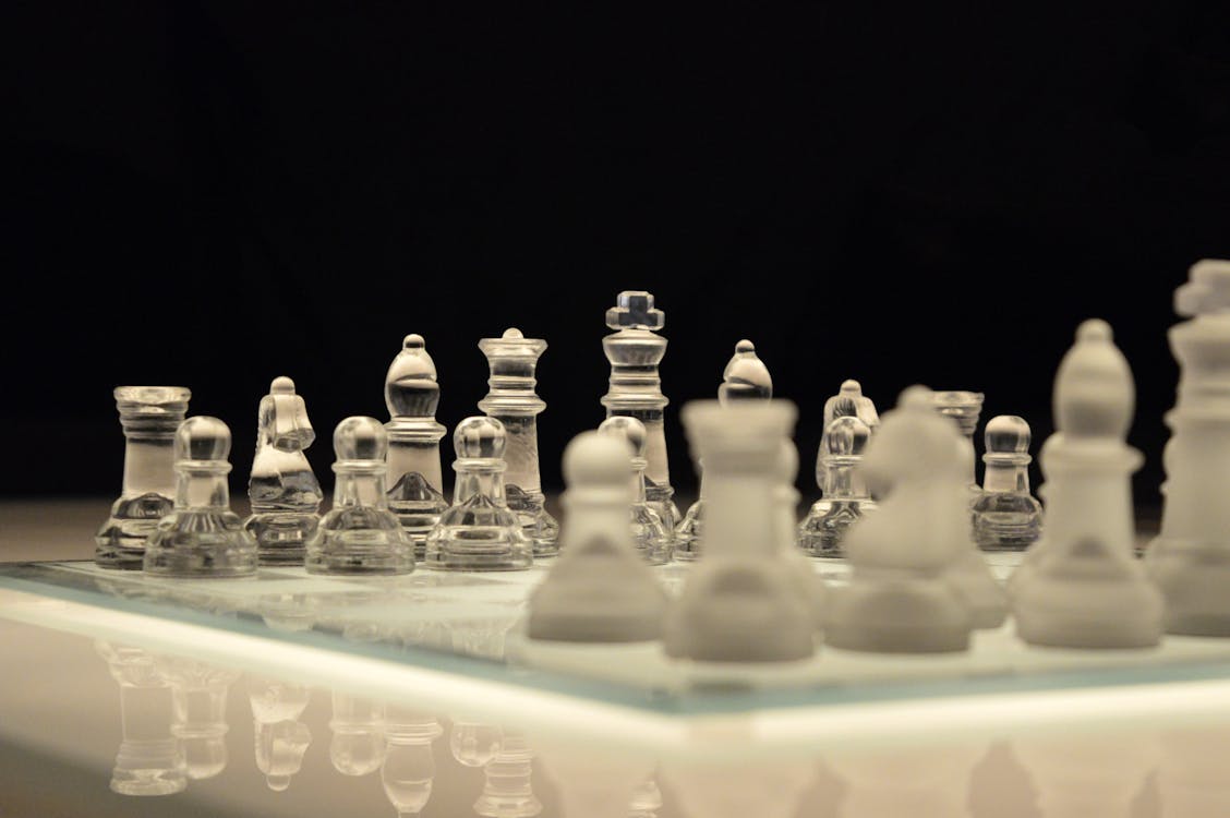 Série de peças de xadrez brancas antes do jogo no tabuleiro preto e branco  sobre fundo preto.