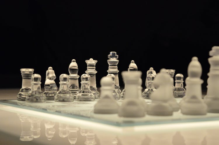 Clear Glass And White Chess Piece On White Chess Board With Black Background