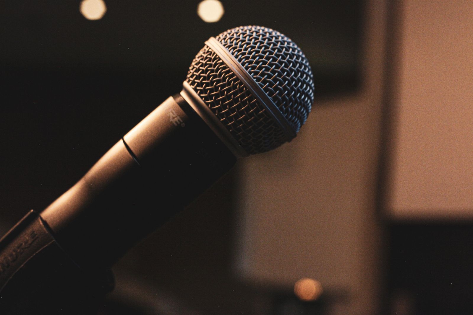 Close-up of a studio microphone glowing in a dark recording room