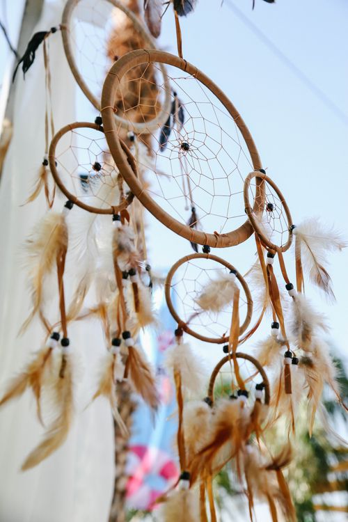 Free Close-up of an artistic dreamcatcher with feathers hanging outdoors. Stock Photo
