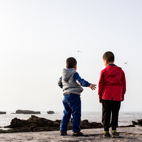 Back View of Two Kids Standing on the Beach Shore