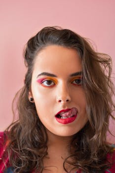 Close-up portrait of a woman with colorful eye makeup, red lips, and playful expression. Captured in Rio.