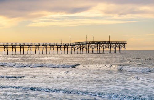 Sea Waves Crashing on Beach Shore Across the Pier