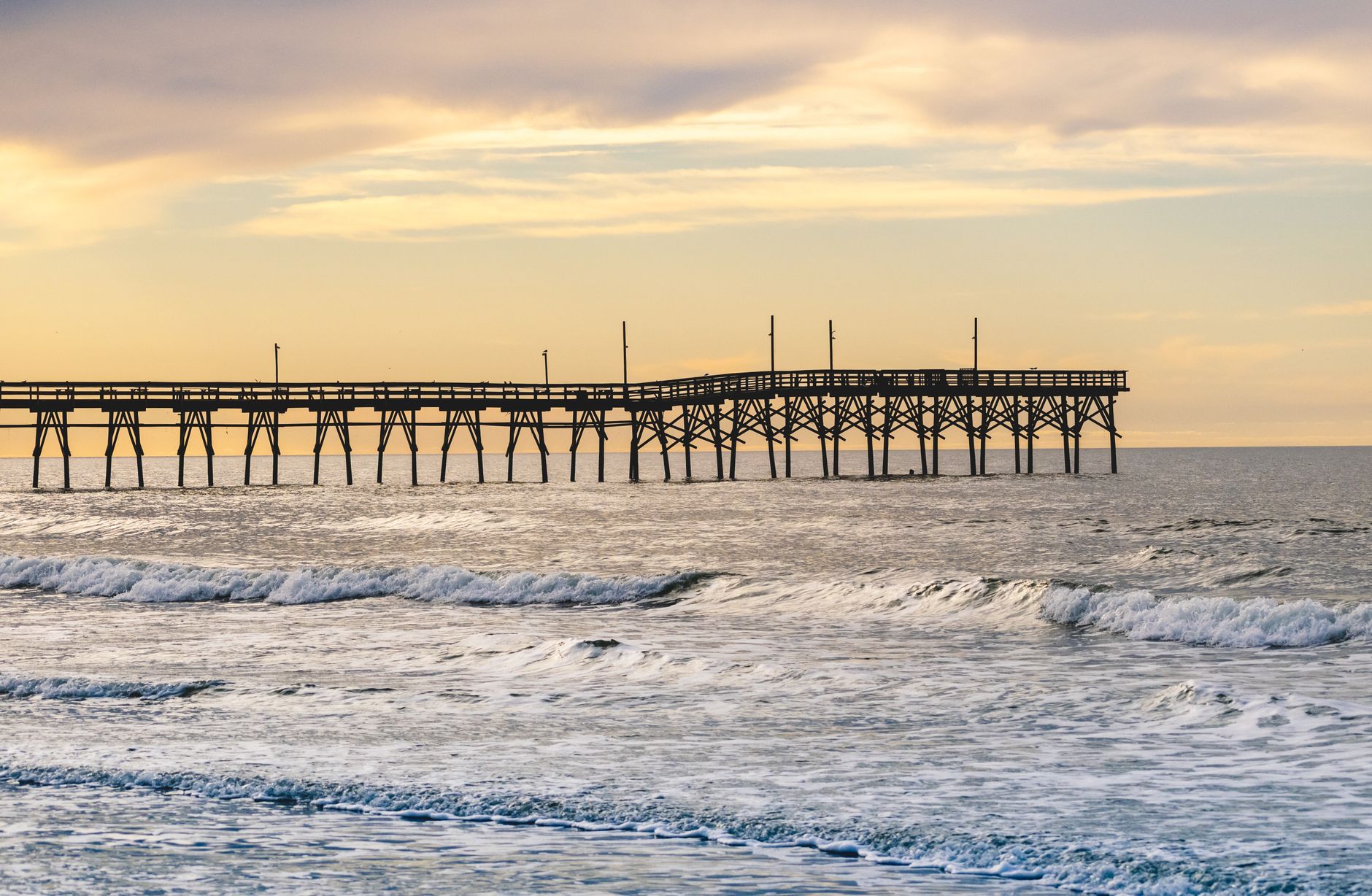 Sunset Beach Pier near Calabash, North Carolina, with gentle Atlantic waves and coastal light.