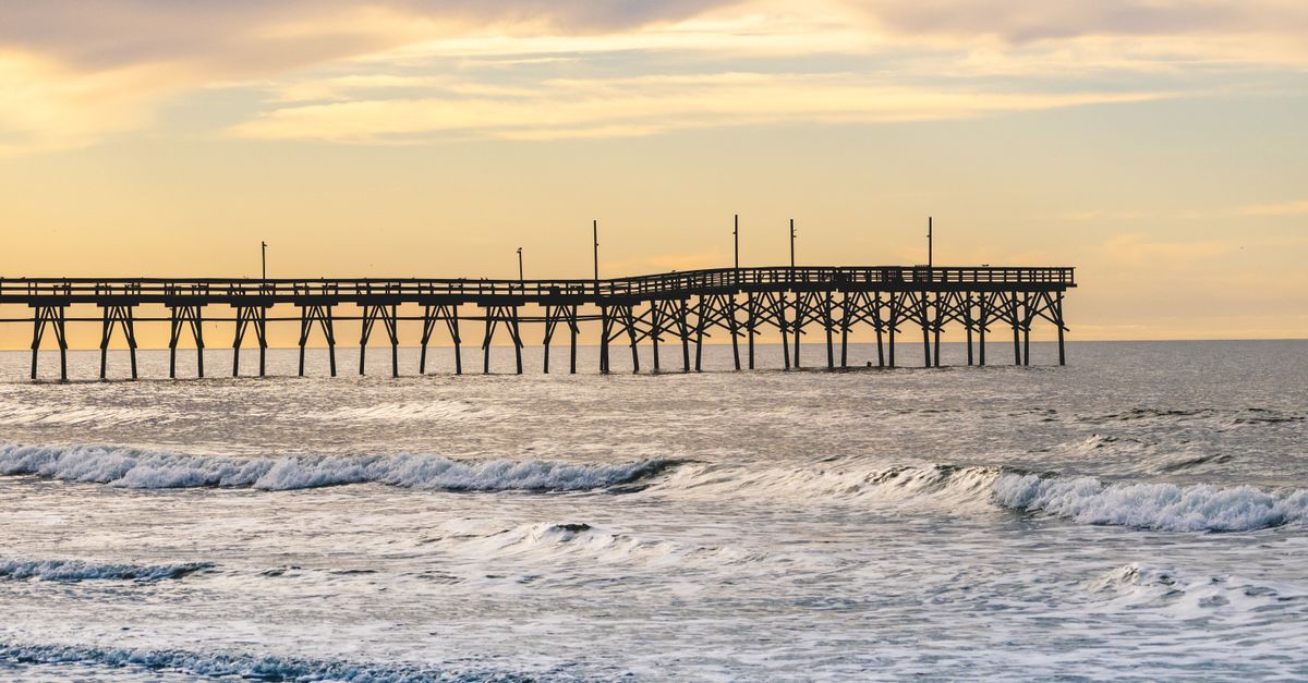 Peaceful evening at Sunset Beach Pier, North Carolina with gentle waves and a colorful sky.