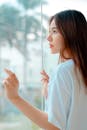 Calm young Asian woman standing near window