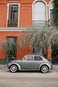 A classic vintage Volkswagen Beetle parked against a vibrant building.