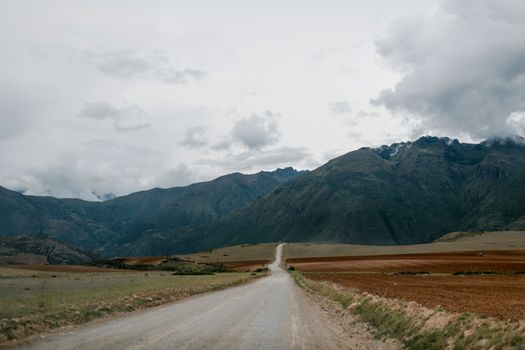 一条宁静的乡村道路穿过风景如画的山地景观，头顶是壮观的天空