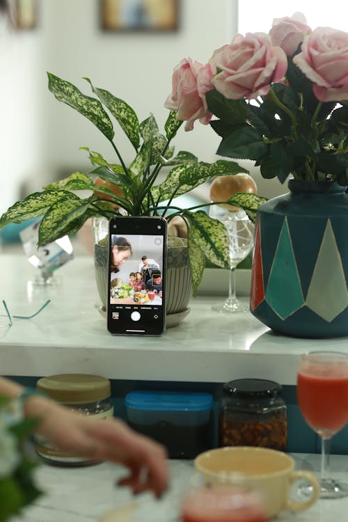 Black and White Iphone Case Beside Green and Red Ceramic Vase